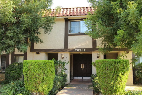 Front view of a two-story house with a tiled roof and a dark double front door.