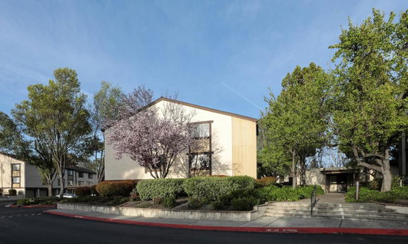 Front view of a mid-sized building with trees and shrubs in front.