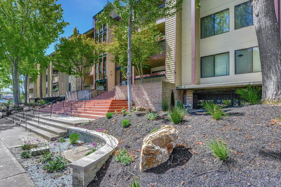 Front view of a multi-story building with outdoor stairs and landscaped garden.