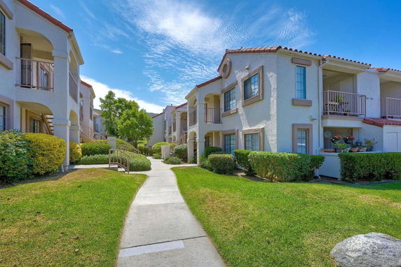 Front view of a two-story apartment building with balconies and landscaped surroundings.