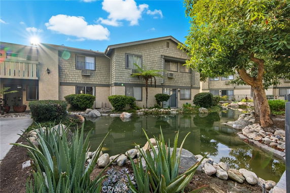 Front view of a multi-story building with a pond and landscaped garden.