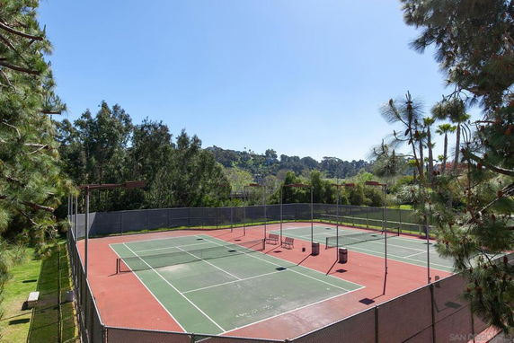 Tennis courts surrounded by trees and fencing.