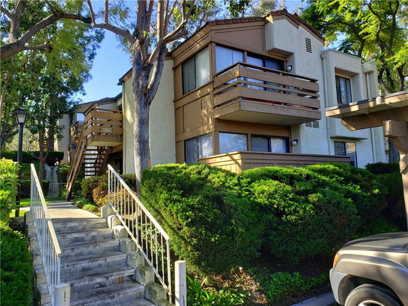 Front view of a two-story residential building with balconies and exterior stairs.