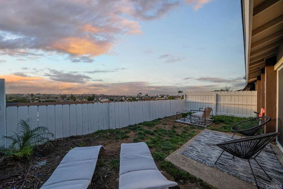 Backyard patio area with a view of distant landscape and cloudy sky.