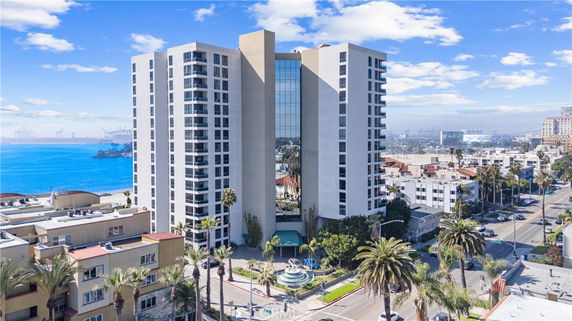 Front view of a tall multi-story building with a modern design and glass facade facing the ocean.