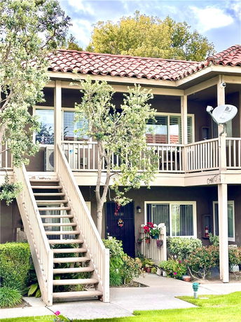 Front view of a two-story building with an exterior staircase and a tiled roof.