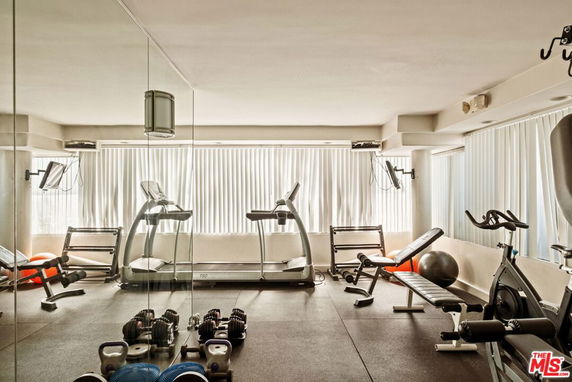 Indoor gym area with fitness equipment including treadmills and weights.