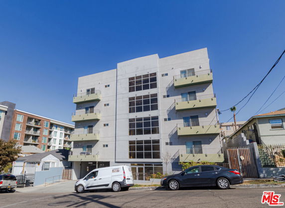 Front view of a multi-story apartment building with balconies and large windows.