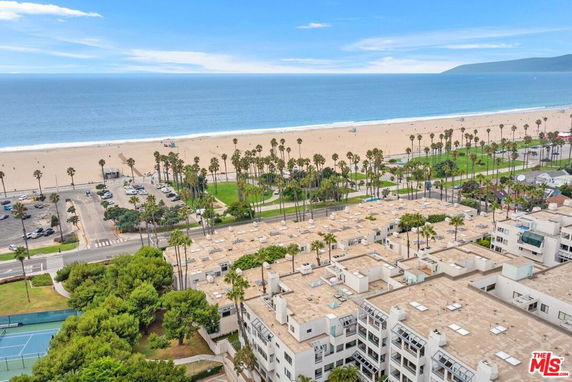High angle panoramic view of beachfront buildings and the coastline with a beach and ocean in the background.