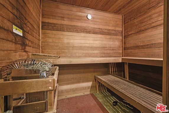 Wood-paneled sauna room with a bench and heating unit.