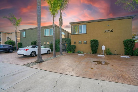 Front view of a two-story building with a parking area in front.