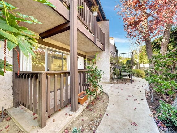 Side view of a two-story house with wooden balcony railing and walkway.