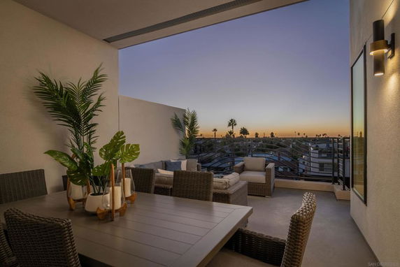Outdoor patio area with furniture overlooking a cityscape during sunset.