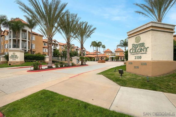 Front view of a multi-story condominium complex with palm trees and entrance signage.