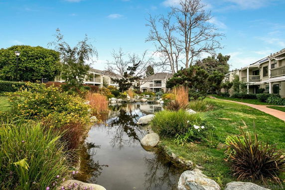 Outdoor view of residential buildings with a landscaped garden and pond.