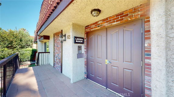 Front view of a building entrance with double doors and a sign reading 'Lagora Manor'.