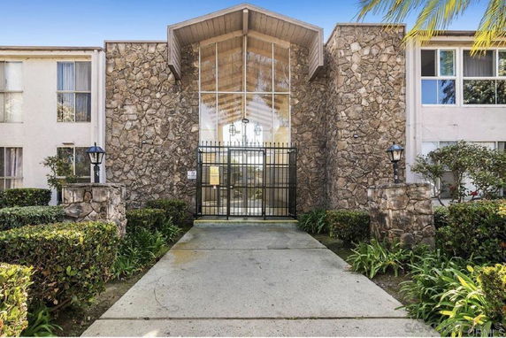 Front view of a stone-faced residential building entrance with large glass panels.