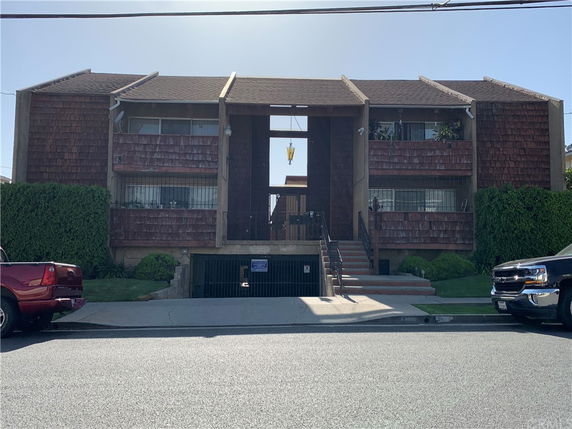 Front view of a mid-century apartment building with wood shingle siding and central entrance.