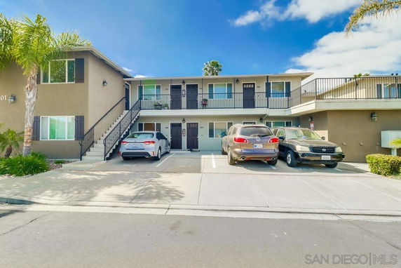 Front view of a two-story apartment building with outdoor parking spaces.
