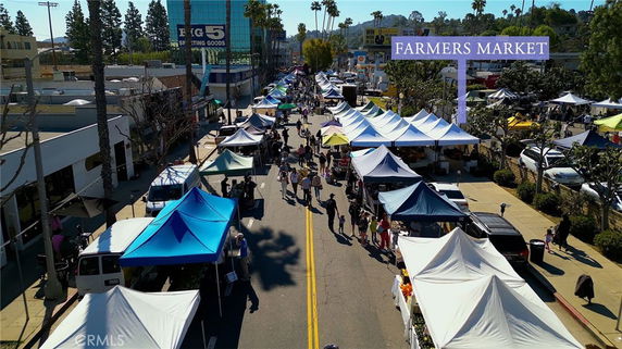 View of a busy street market with tents and people.