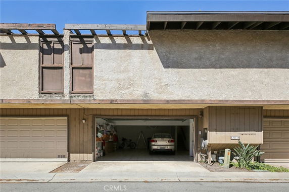 Front view of a townhouse with an open garage and two windows above.