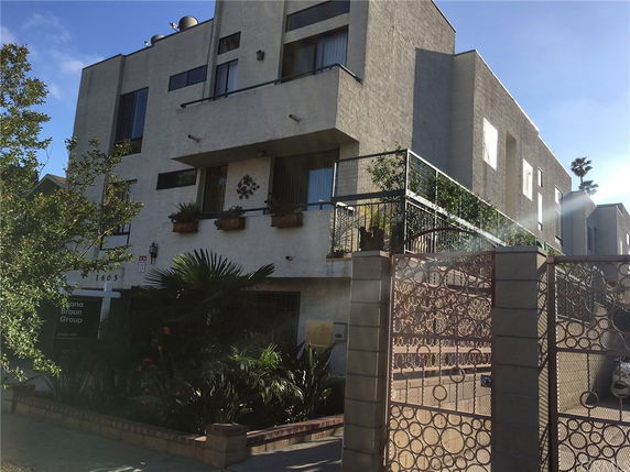 Front view of a multi-story residential building with balconies and a decorative fence.