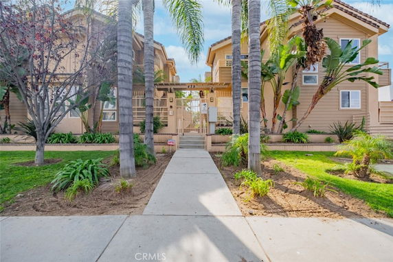 Front view of a multi-story residential building with pathway and palm trees.