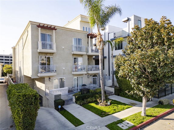 Front view of a multi-story building with balconies and palm trees.