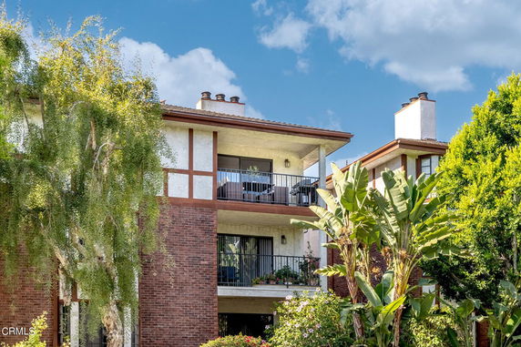 Front view of a multi-story building with balconies and chimney.