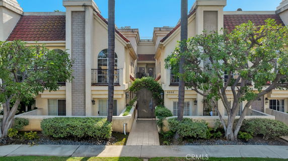 Front view of a two-story residential building with red tile roof and arched windows.