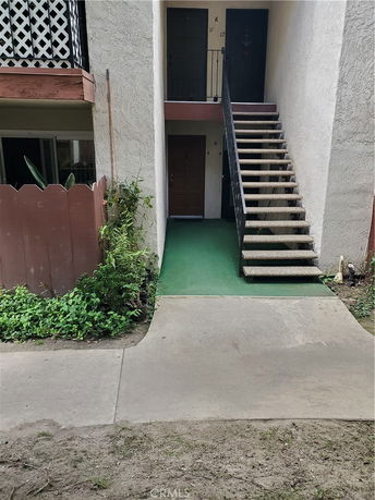 Front view of a small apartment building with stairs leading to an upper floor entrance.