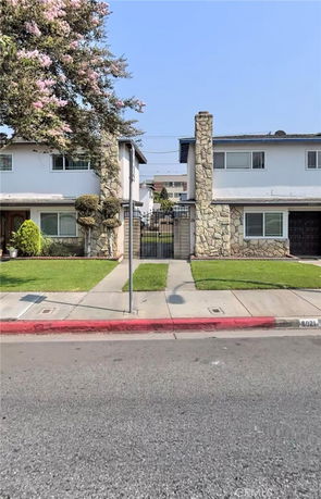 Front view of two adjacent two-story houses with stone accents and gated entrance.