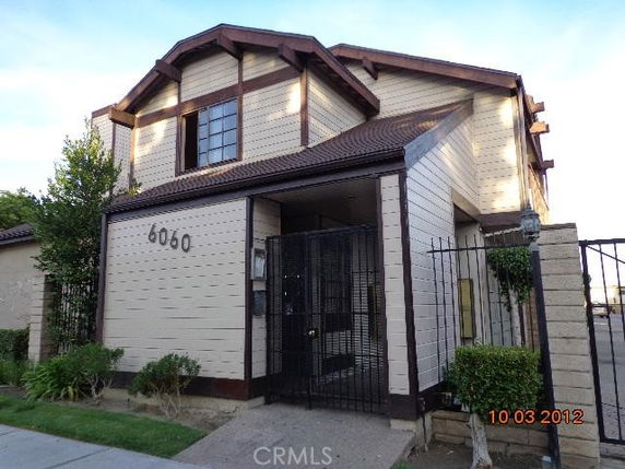 Front view of a two-story house with a gated entrance and distinctive wooden siding.