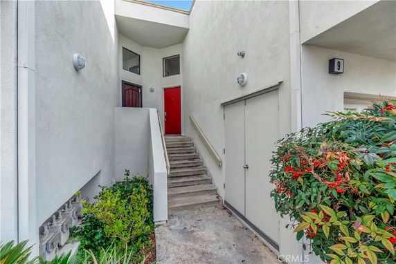 Front view of a building entrance with stairs leading to a red door.