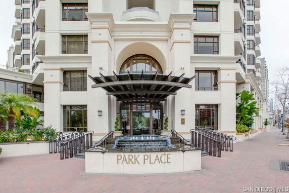 Front view of a multi-story building with large entrance and decorative fountain.