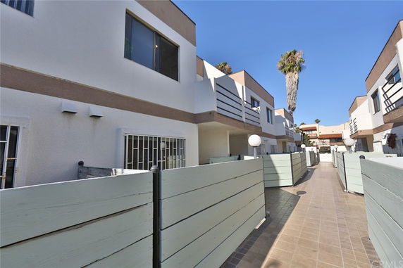 Front view of a series of two-story townhouses with balconies and enclosed patios.