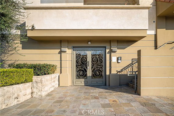 Front view of a building entrance with decorative metal doors and stone walkway.