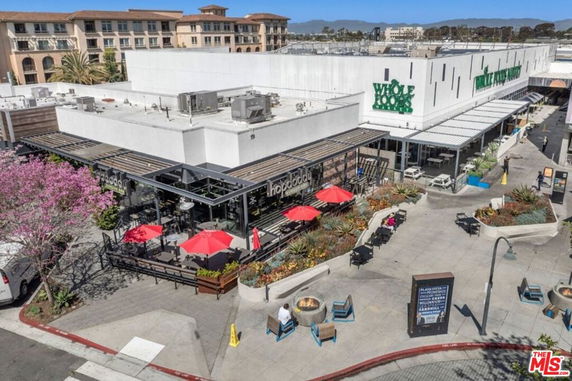 Front view of a shopping complex with outdoor dining and signage.