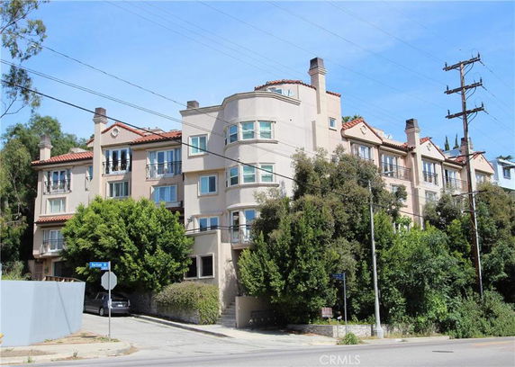 Front view of a multi-story residential building with balconies and chimneys.