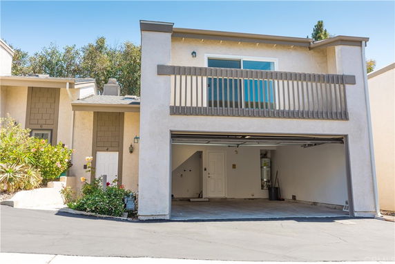Front view of a two-story house with a garage and a balcony.