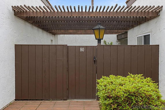Front view of a house entrance with a wooden gate and pergola.