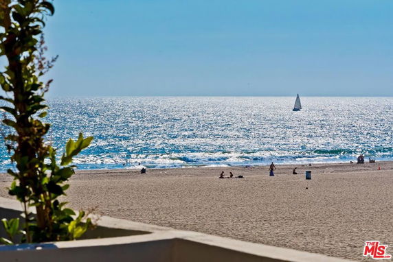 Beach view with people and a sailboat on the ocean