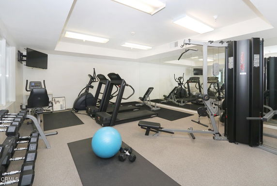 Indoor gym area with exercise equipment, including treadmills and weights.