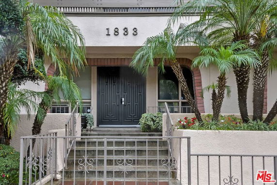 Front view of a building with a gated entrance and palm trees.