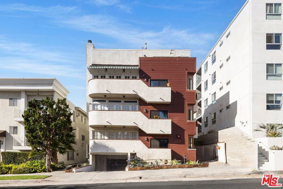 Front view of a multi-story building with a modern design and balconies.