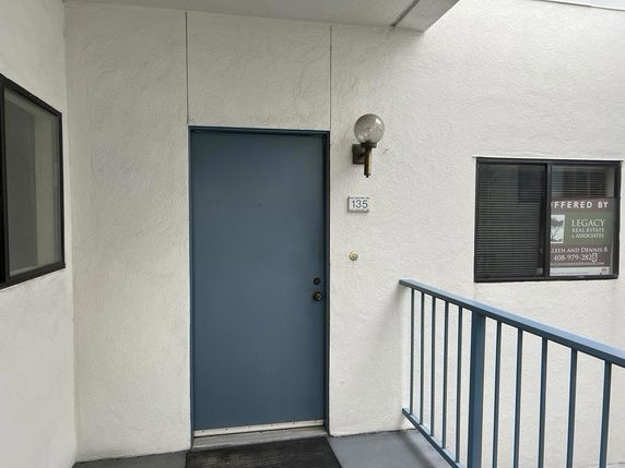 Front view of a building entrance with a blue door and a railing.