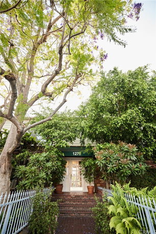 Front view of a house entrance with brick steps and surrounded by greenery.