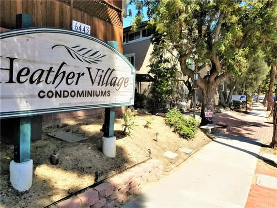 Front view of a condominium complex entrance with a sign that reads 'Heather Village Condominiums'.