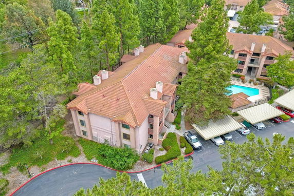 Aerial view of a residential complex with a swimming pool, surrounded by trees.
