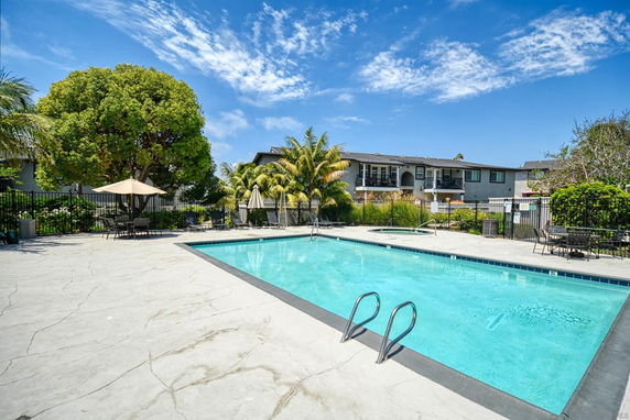 Outdoor swimming pool area with surrounding trees and residential building.